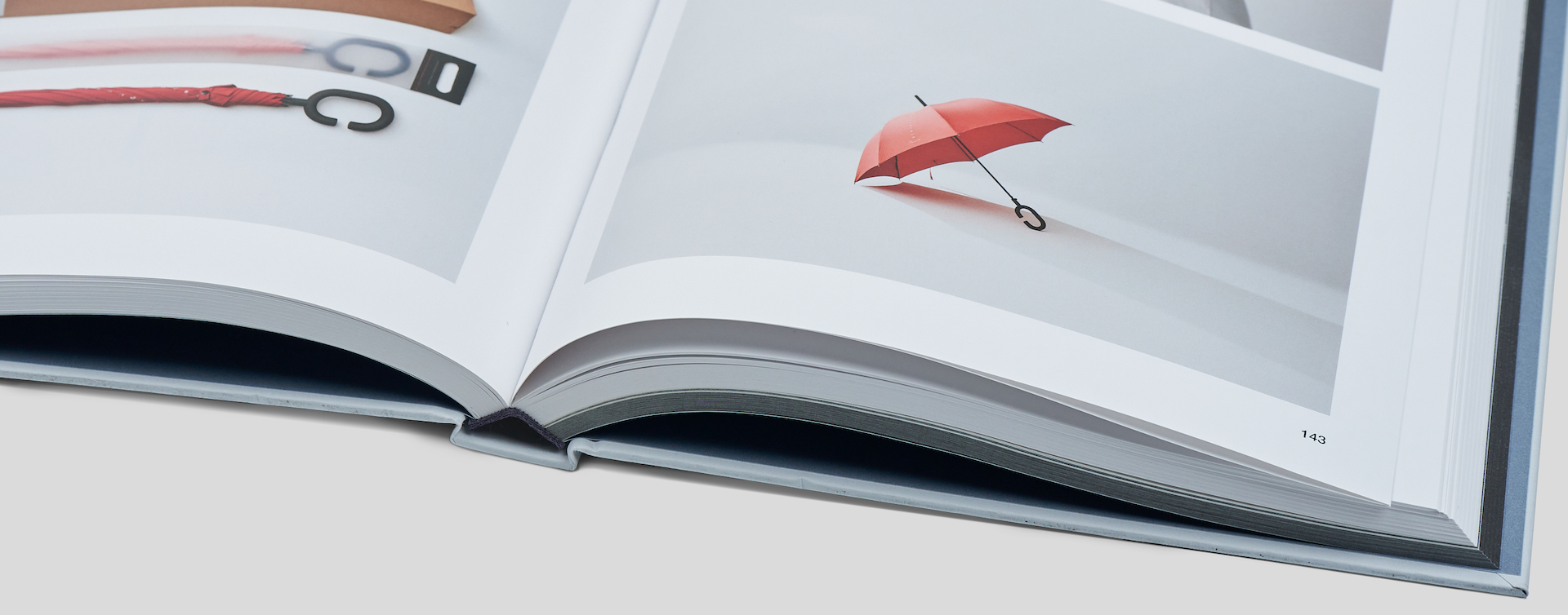 Spine-focused close-up of an opened coffee table book, emphasizing the strong binding and premium finish