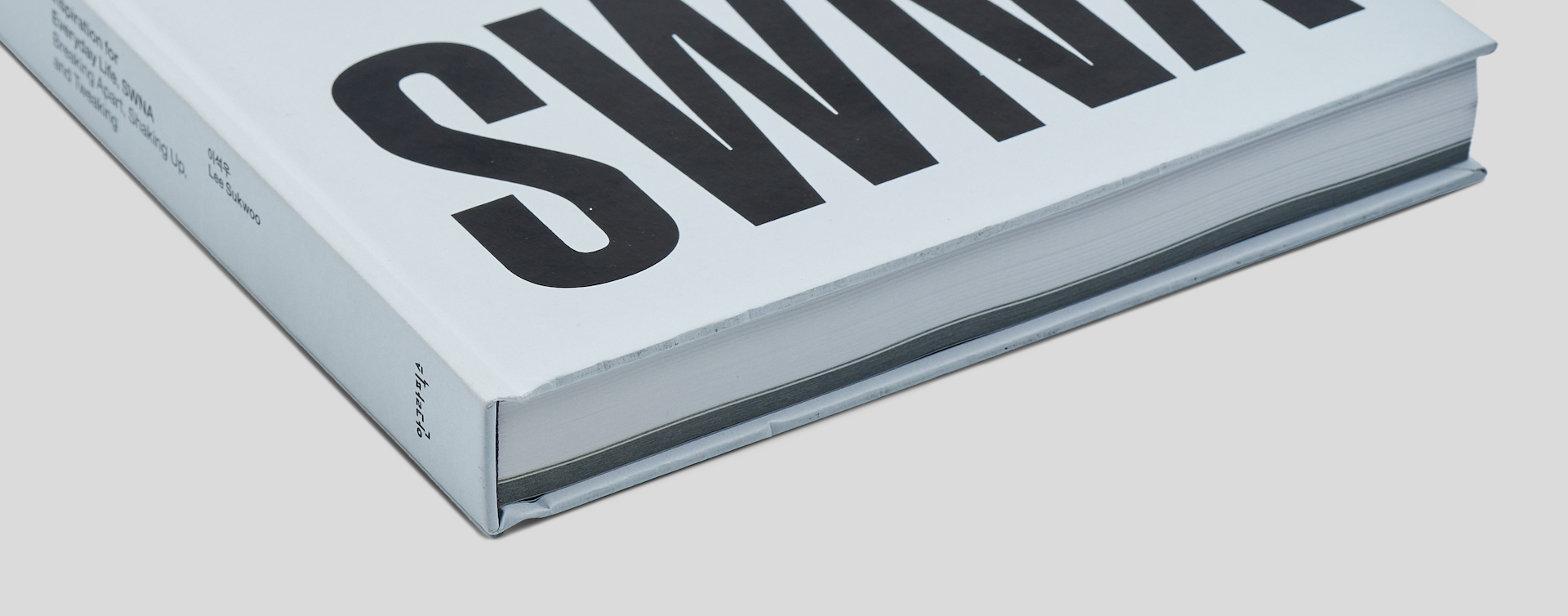 Close-up of the bottom spine of a squared hardcover coffee table book, showing excellent build quality and sharp edges