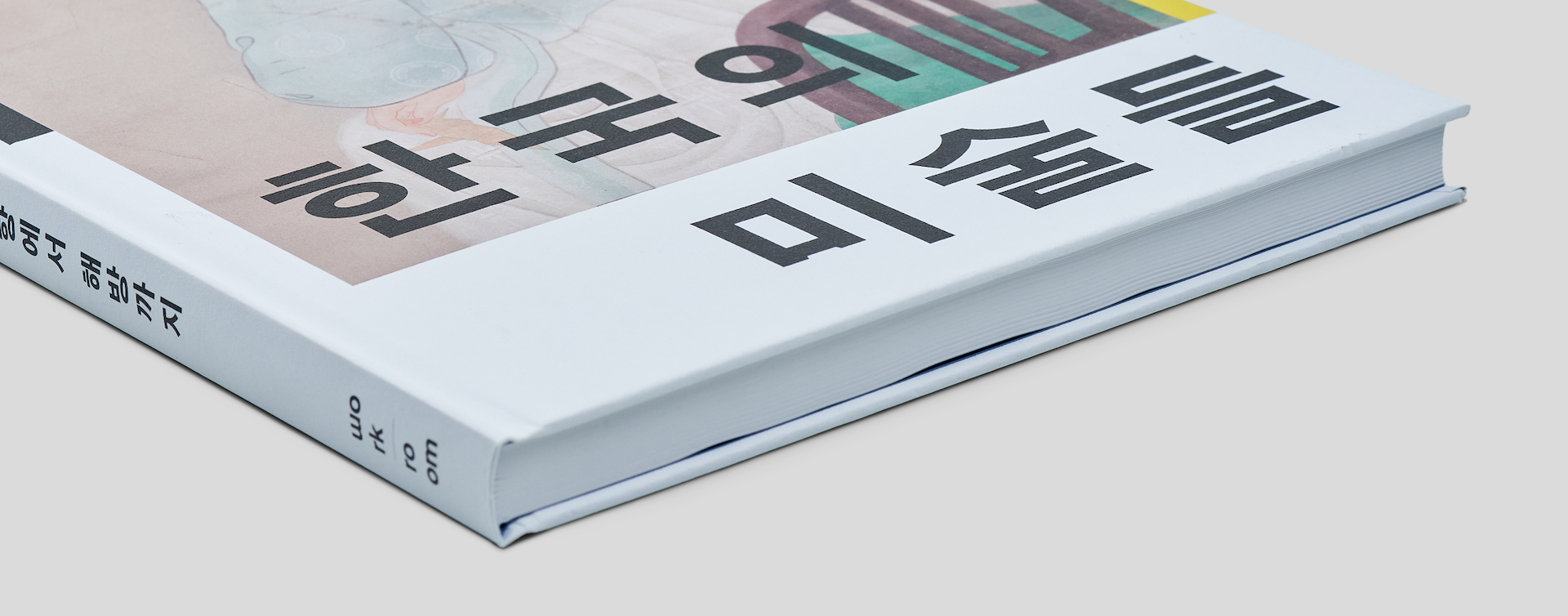 White cover hardcover book with round spine, close-up of spine and bottom edge to emphasize build quality