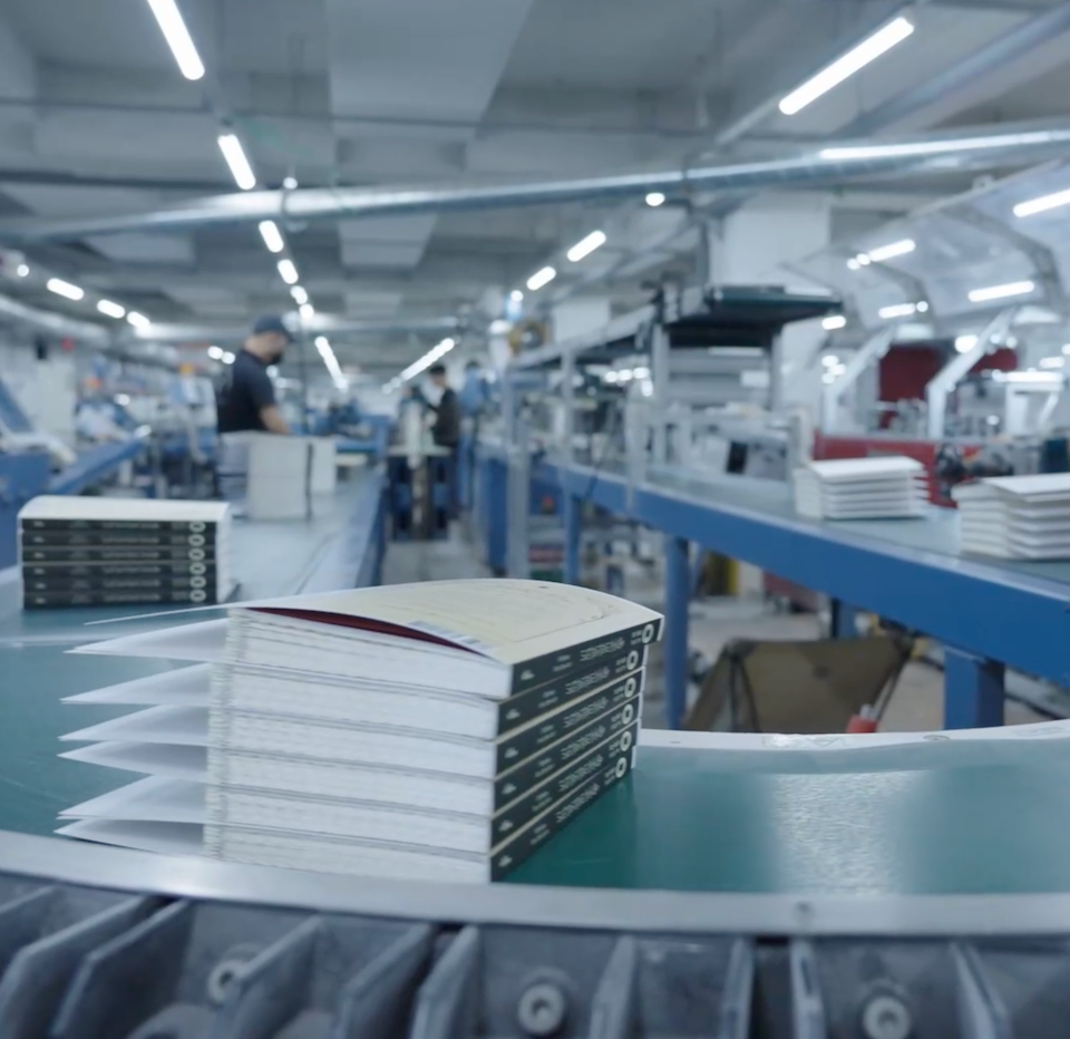 Softcover binding line at inclpress with books stacking on the conveyor during production