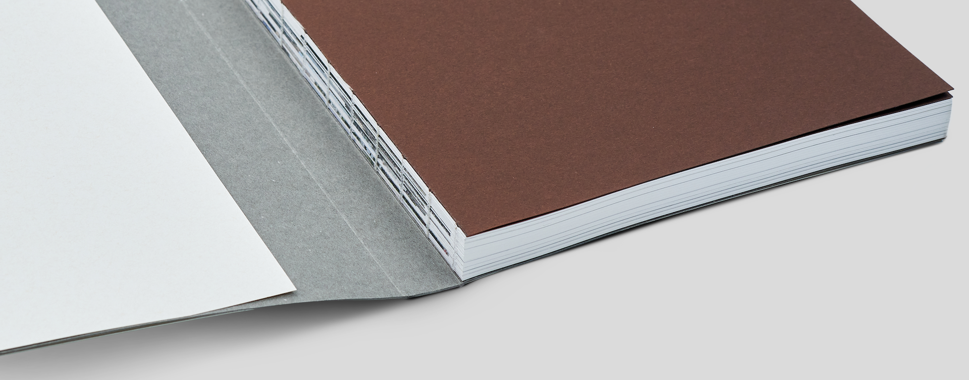 Swiss-bound book with front cover open, exposing the spine and visible sewn binding